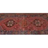 A large Persian Islamic red ground Heriz floor rug having central twin medallions with geometric