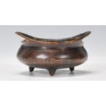 A cast bronze Chinese censer bowl of small proportions being open topped, raised on three feet