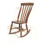 A Victorian 19th century beech and elm windsor rocking chair. Raised on turned legs united by