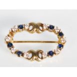 A 9ct gold brooch of oval form set with alternate white and blue stones with a hinge pin to verso.
