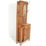 A 1930's Art Deco oak hallstand. The upright back with mirror and hooks over half moon shelf,