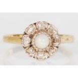 A stamped 18ct gold ladies ring having a flower head set with a central round opal with white