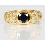 An 18ct gold ring set with an oval cut sapphire with stepped shoulders set with diamond accent