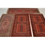 A  collection of Persian / Islamic rugs to include a pair of red ground tribal rugs with double
