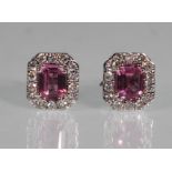 A pair of ladies 18ct white gold stud earrings set with rectangular cut pink sapphires with a halo