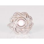 A ladies Art Deco style dress ring having a pierced knot design head surrounding a round opal