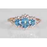 A hallmarked 9ct yellow gold ring set with a central oval faceted cut blue topaz flanked by two