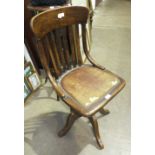 An early-20th century stained beech swivel office chair, with trademark label 'Made in England'.