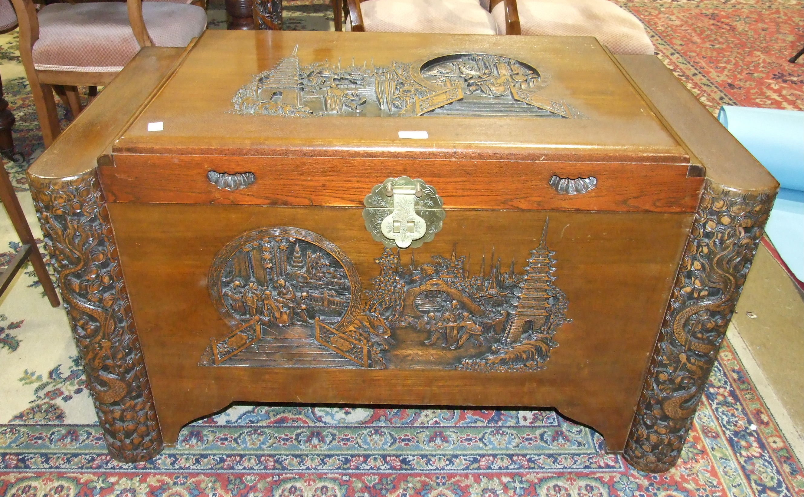 A 20th century camphor-wood-lined blanket box, the front and lid carved with figures and pagoda,