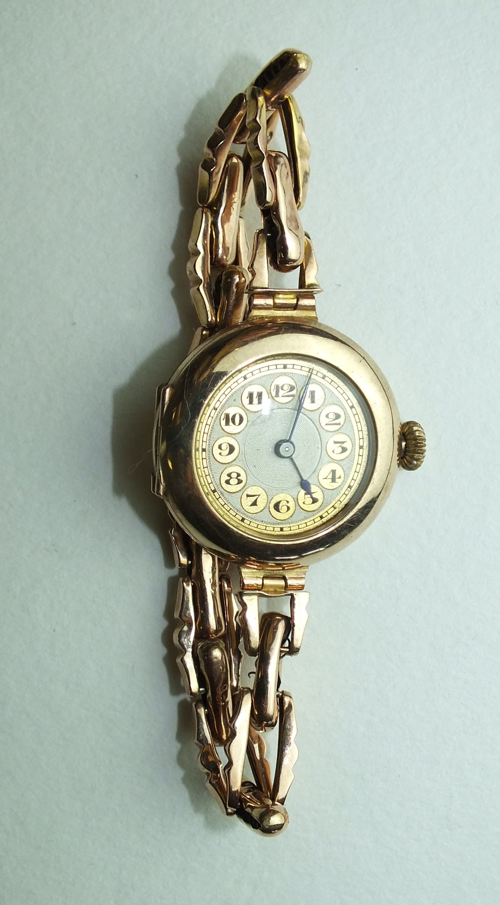 A ladies 9ct-gold-cased wrist watch, the circular gold dial with Arabic numerals, on 9ct gold sprung