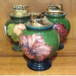 Three Moorcroft baluster-shaped green-glazed table lighters decorated in the Hibiscus pattern,