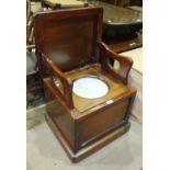 A mahogany box commode, the seat enclosing a ceramic chamber pot and hinged arm supports, 51.5cm