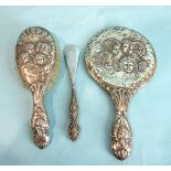 A silver-backed hand mirror and hair brush embossed with winged cherubs and a silver-handled shoe