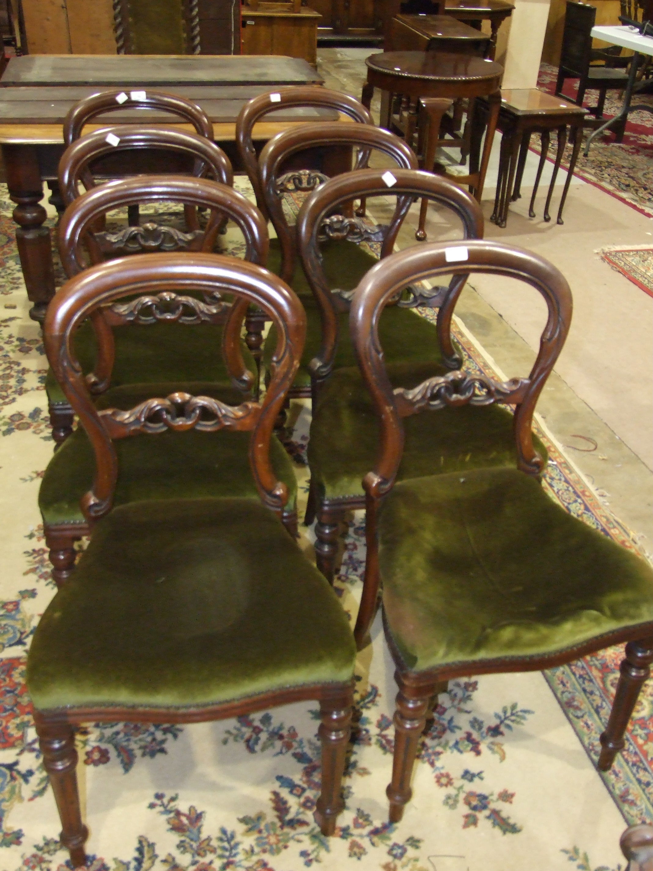 A set of eight Victorian-style balloon-back mahogany dining chairs with serpentine seats.