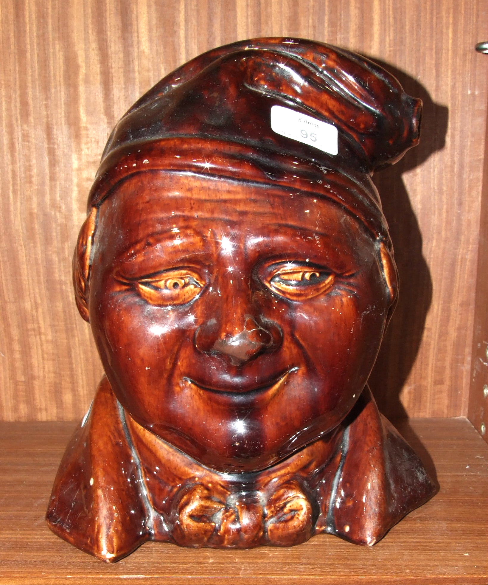 A large treacle-glazed flask modelled as the head of a man wearing a night cap, its end forming