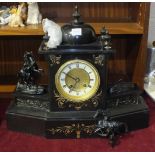 A late-19th century black slate striking mantel clock surmounted on the sides by a pair of spelter