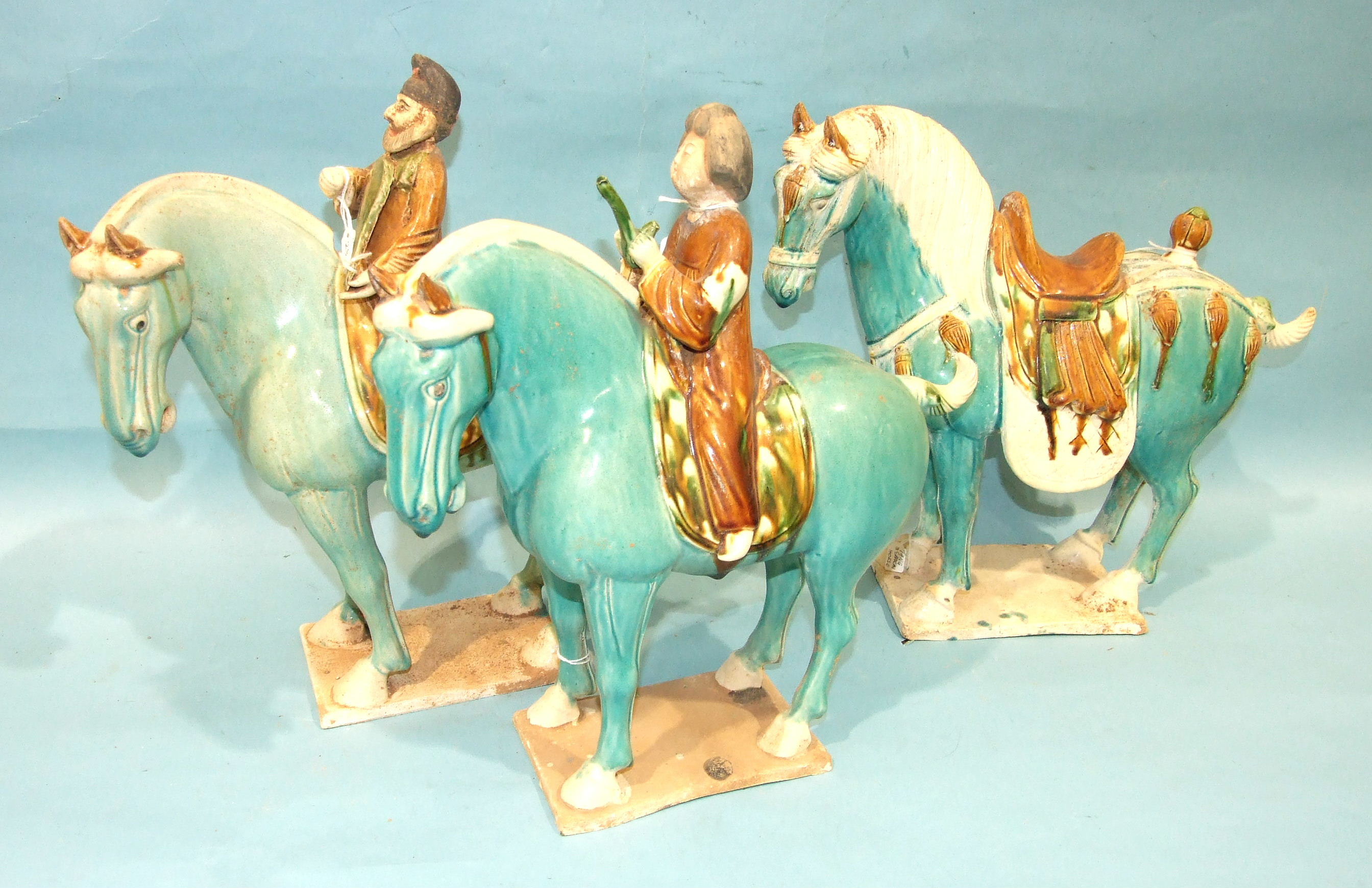 Three Tang-style earthenware sancai horses, two with riders, in a turquoise glaze.