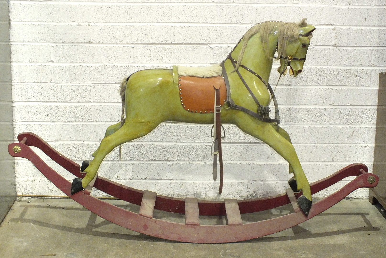 An early-20th century painted wood rocking horse on painted sleigh base and fitted with leather