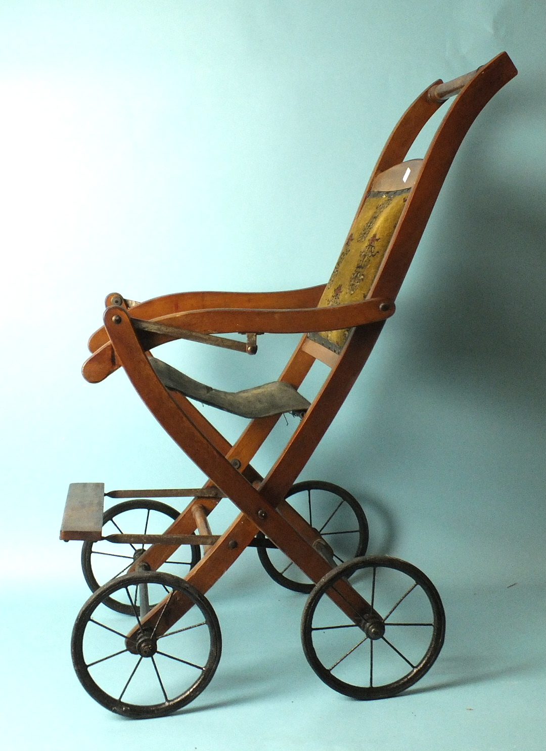 An Edwardian folding push chair with upholstered chenille back and spoked wheels, 82cm high.