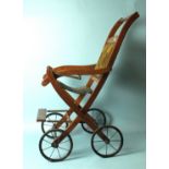 An Edwardian folding push chair with upholstered chenille back and spoked wheels, 82cm high.