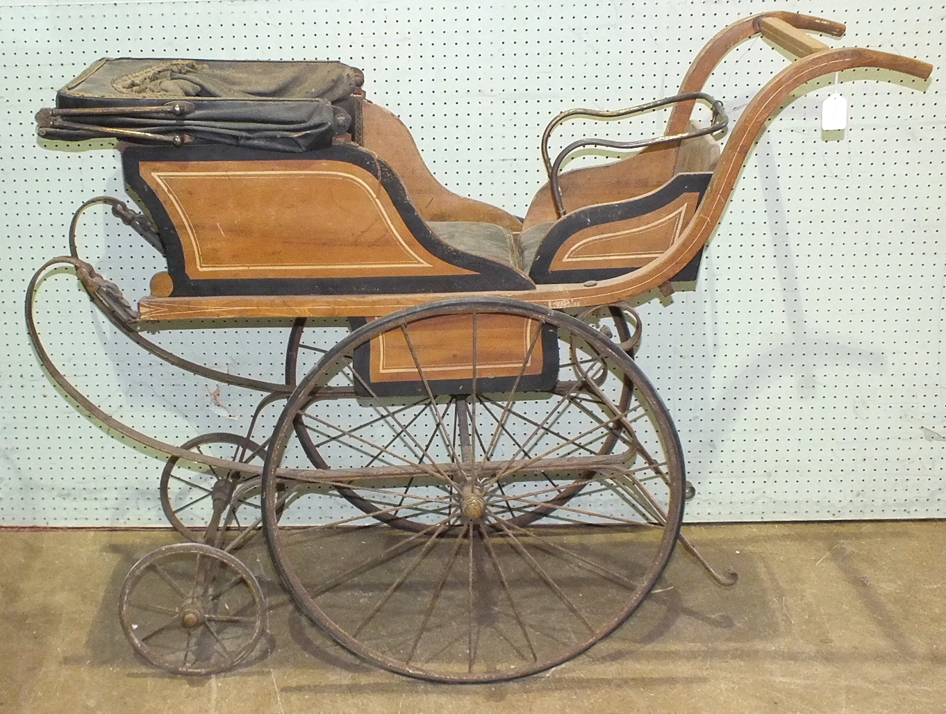 A Victorian child's carriage with wood body folding to make and extra seat, on sprung chassis to