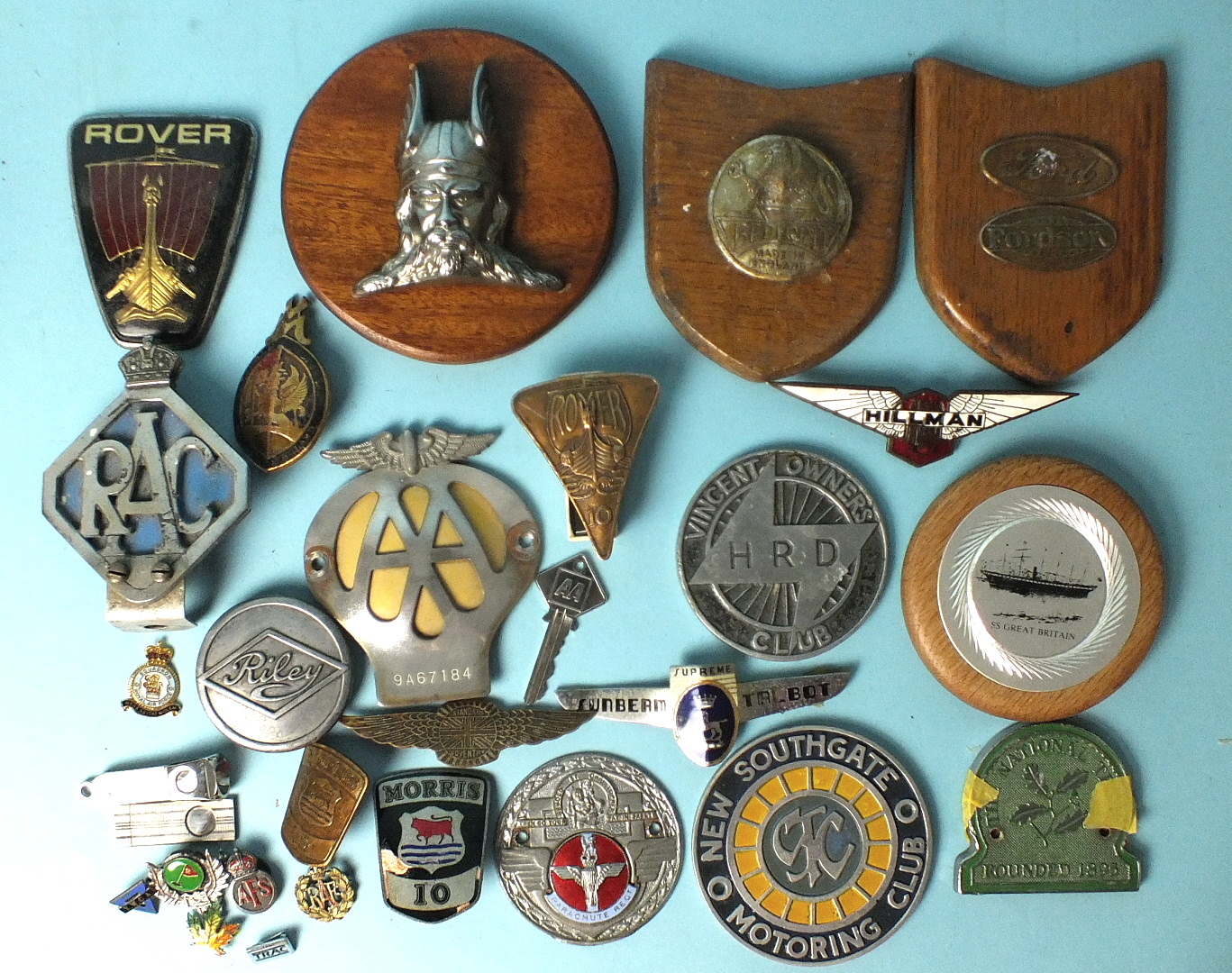 A collection of car badges, including Rover, RAC, AA (9A67184), Fordson, Morris, two cigar