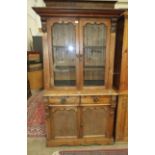 A late-19th century stained pine bookcase, the top fitted with a pair of glazed doors above two