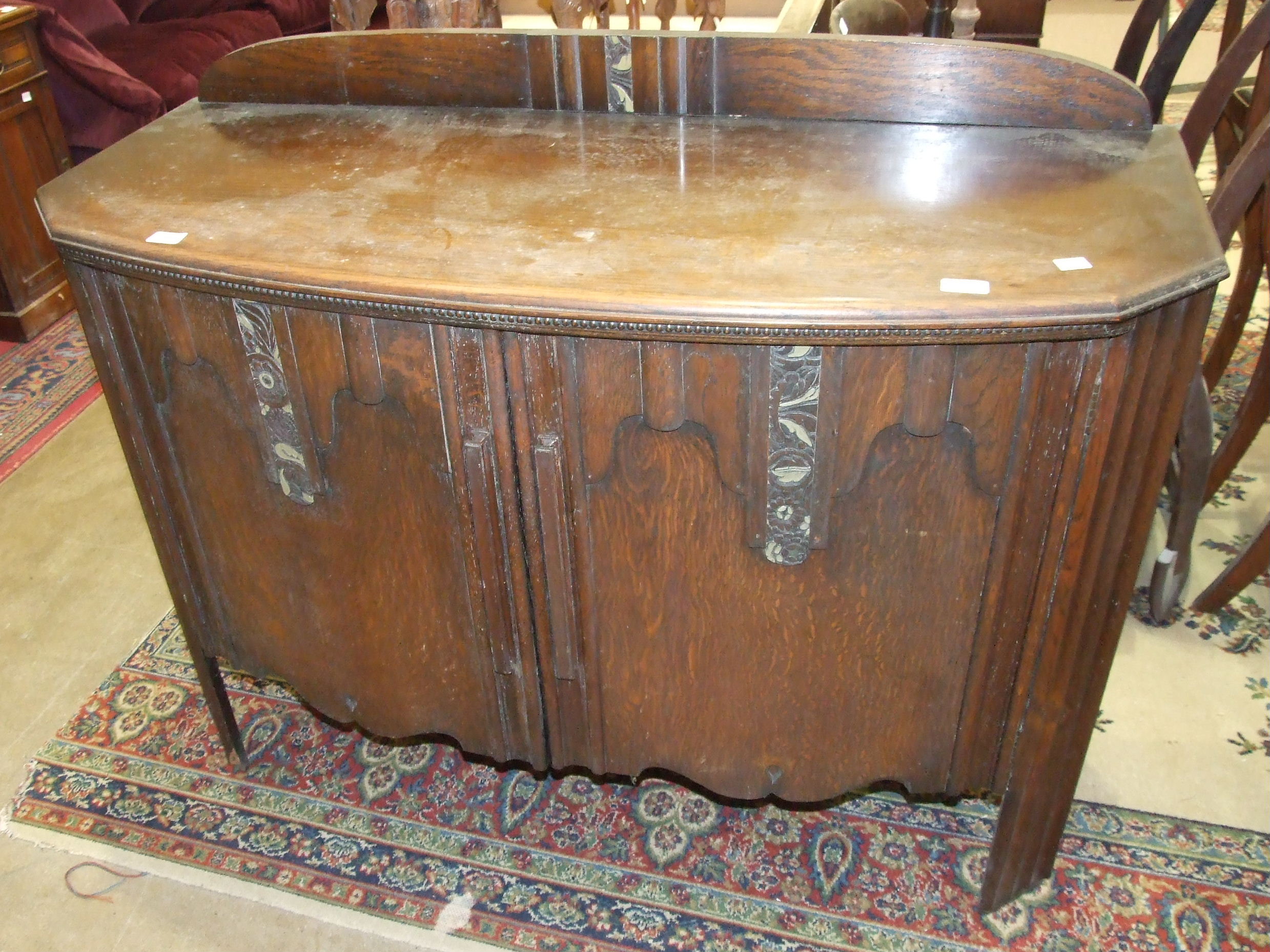 A 1950's oak sideboard, the doors with barbola work panels, 123cm wide.