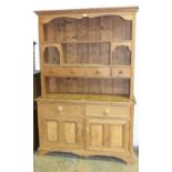 A stripped pine dresser, the open shelved back fitted with four small drawers, above two frieze