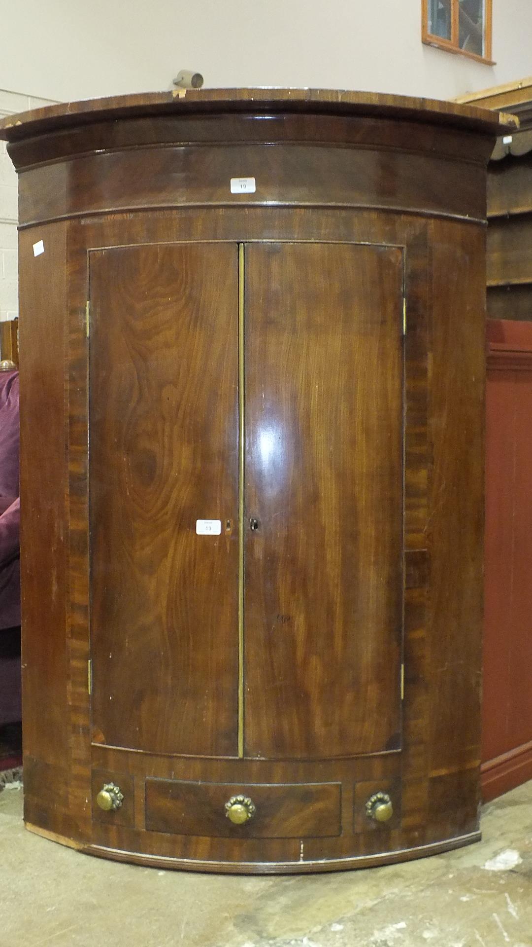 A Georgian mahogany bow-front corner cupboard.