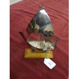 A white metal model of a dhow, on wood stand, 18cm high, in fitted box.