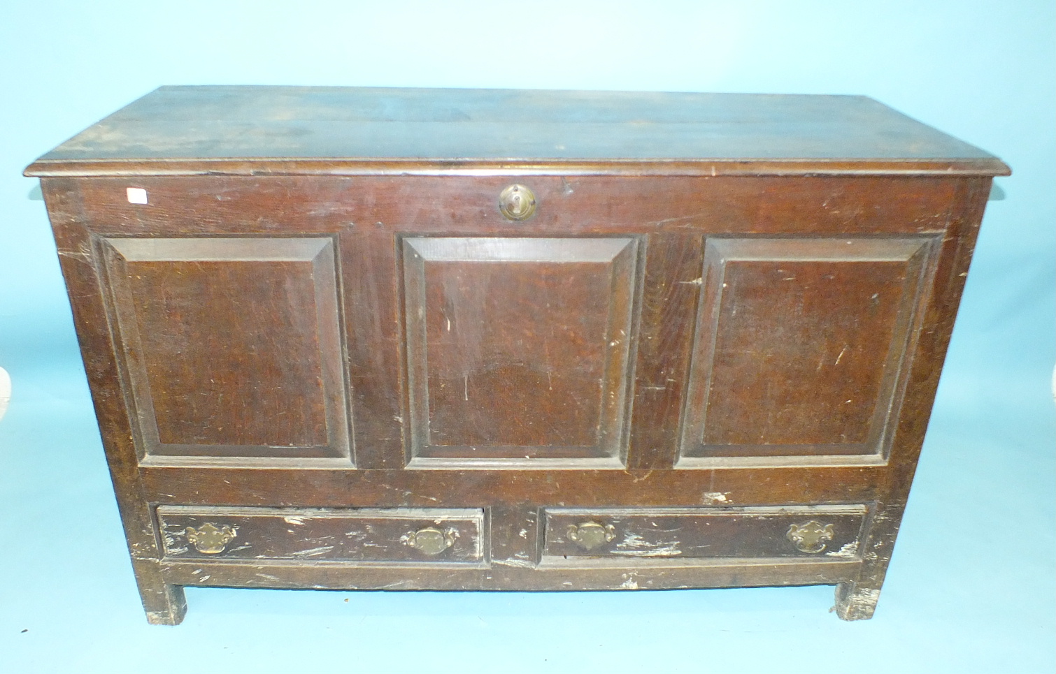 An 18th century oak mule chest, the hinged lid above fielded plain panels and two base drawers,