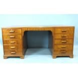 A 1950's mahogany office desk with an arrangement of ten drawers, the top with inset writing