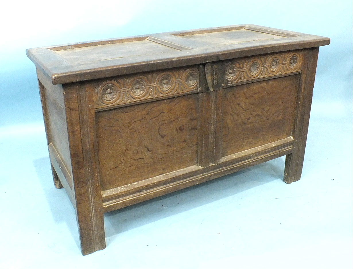 A 17th/18th century small coffer, the two-panel lid above a carved frieze and panel body, the stiles