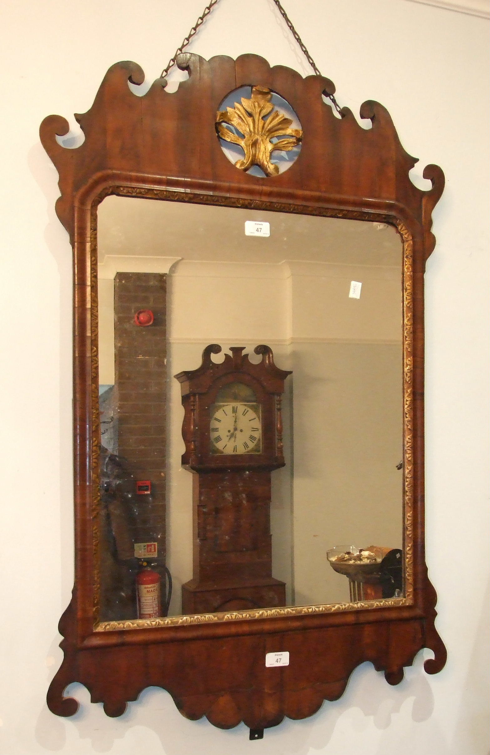 An 18th century walnut and parcel gilt wall mirror, the frame of shaped outline, with pierced