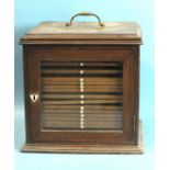 A 19th century walnut coin or collector's chest, having brass carrying handle and glazed door