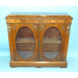 A Victorian walnut and ormolu-mounted side cabinet having a pair of doors with oval glazed panels,
