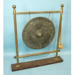 A circular bronze gong with central raised boss on later brass stand with beater, gong 55cm
