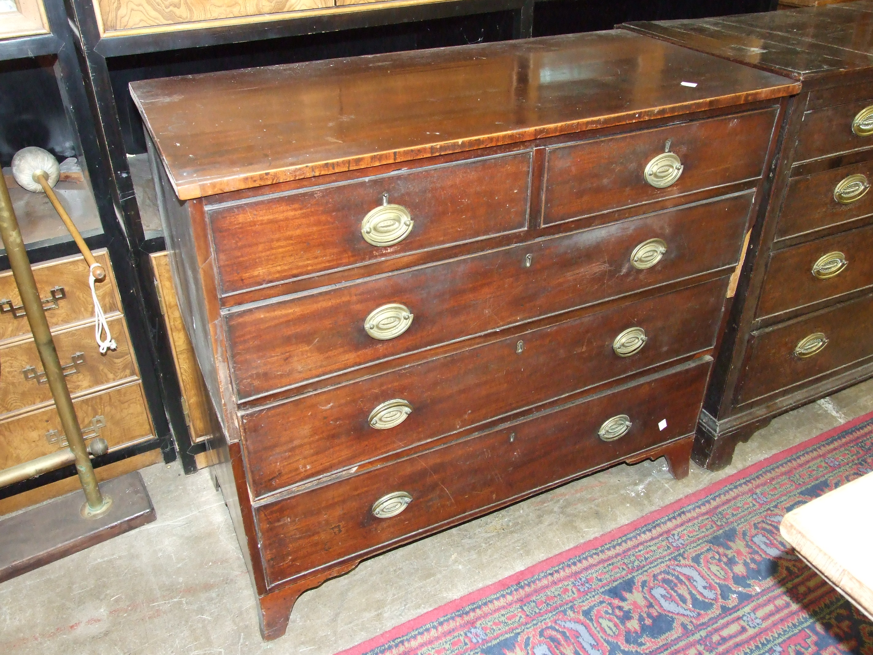 A Georgian mahogany chest of two short and three long cockbeaded drawers on bracket feet, in two