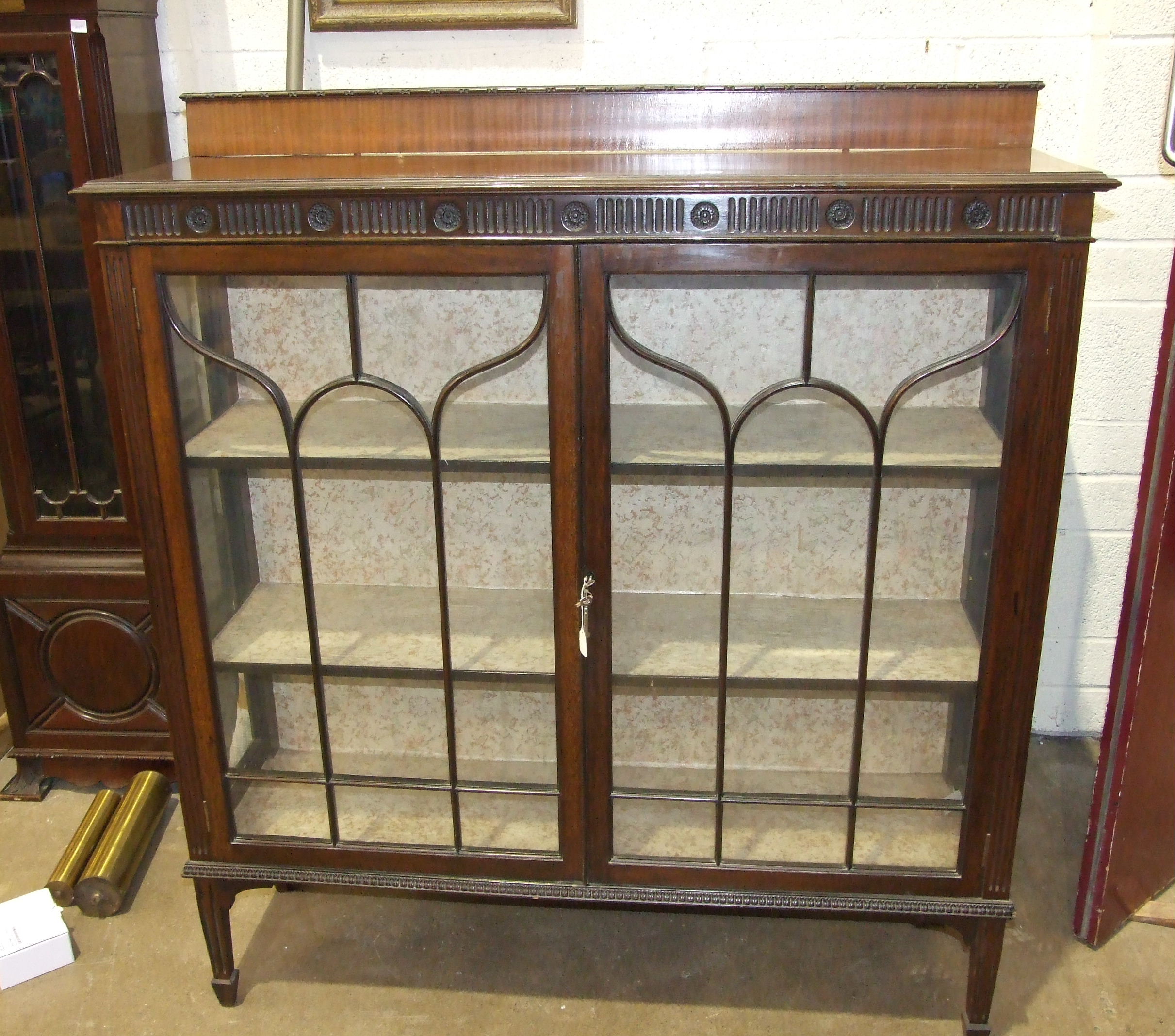 A mahogany display cabinet the rectangular top above a pair of astragal glazed doors on square