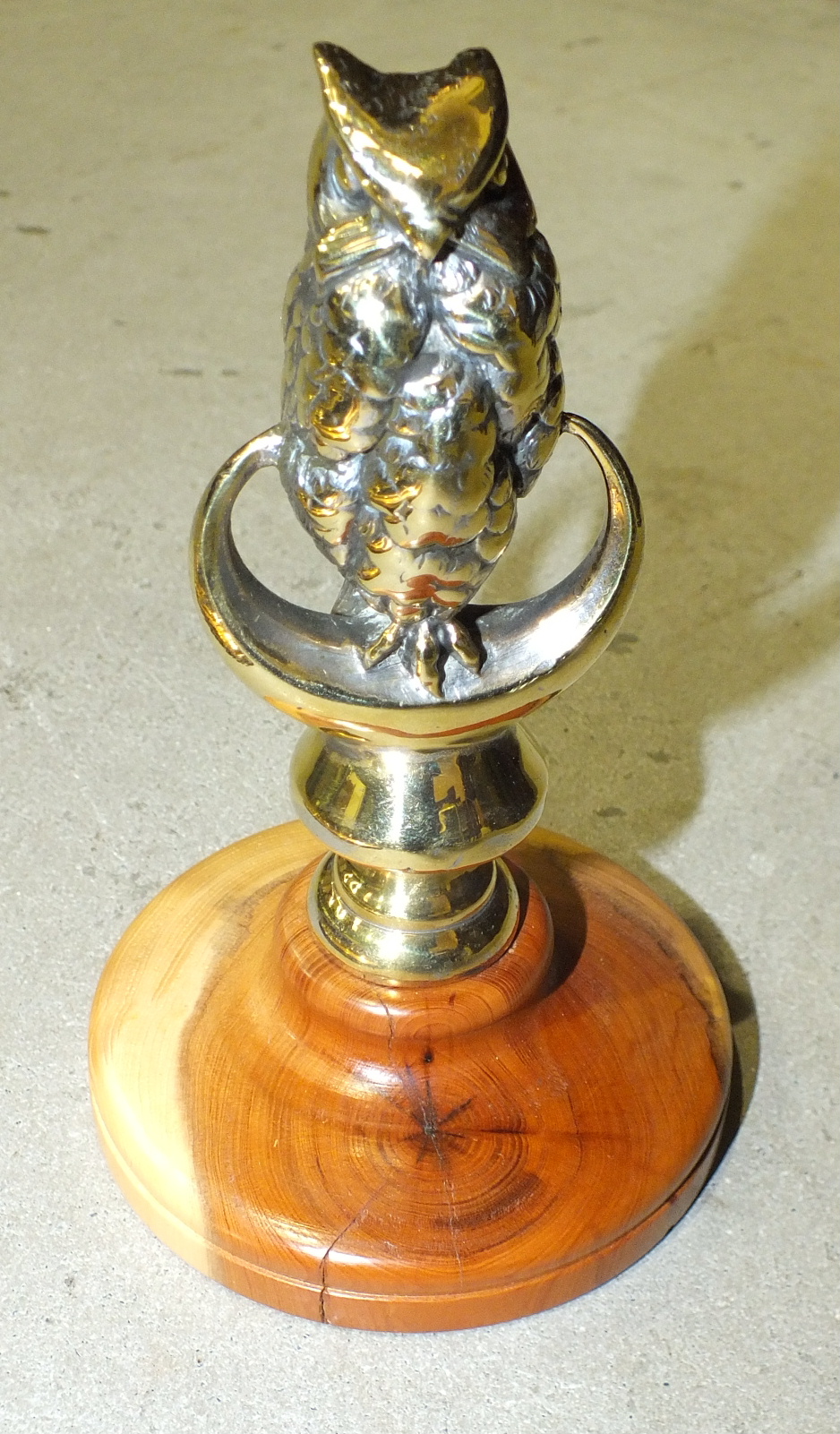 A polished plated brass car mascot in the form of an owl, 11cm high, a brass candle holder by Palmer