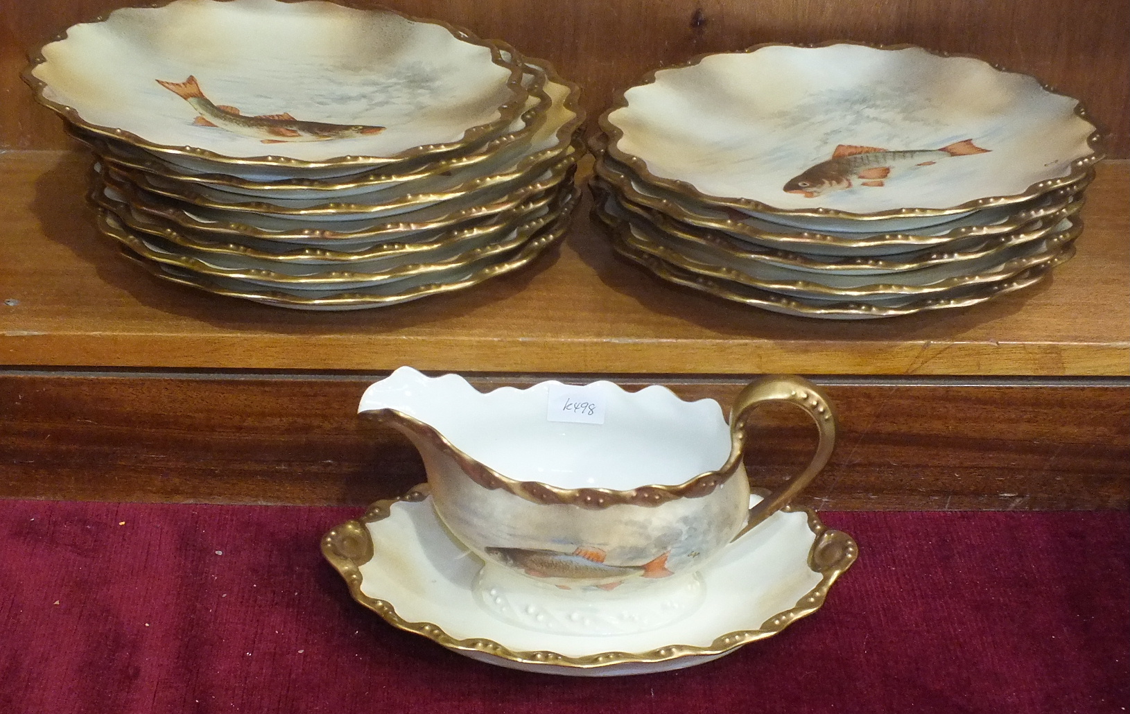 A Limoges painted porcelain fish service, comprising twelve circular plates and a sauce boat on