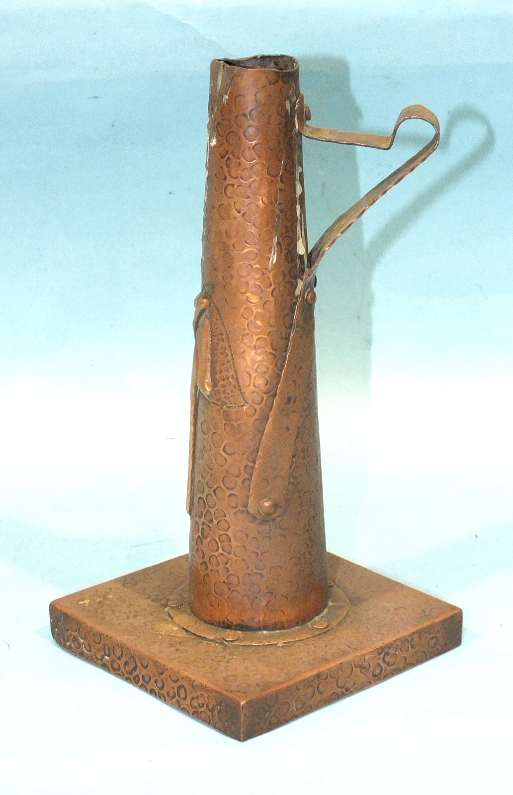 An Arts & Crafts copper candle holder of tapering form, on square base, 20cm high.