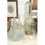 Three glass domes, three cut-glass decanters and other glassware.