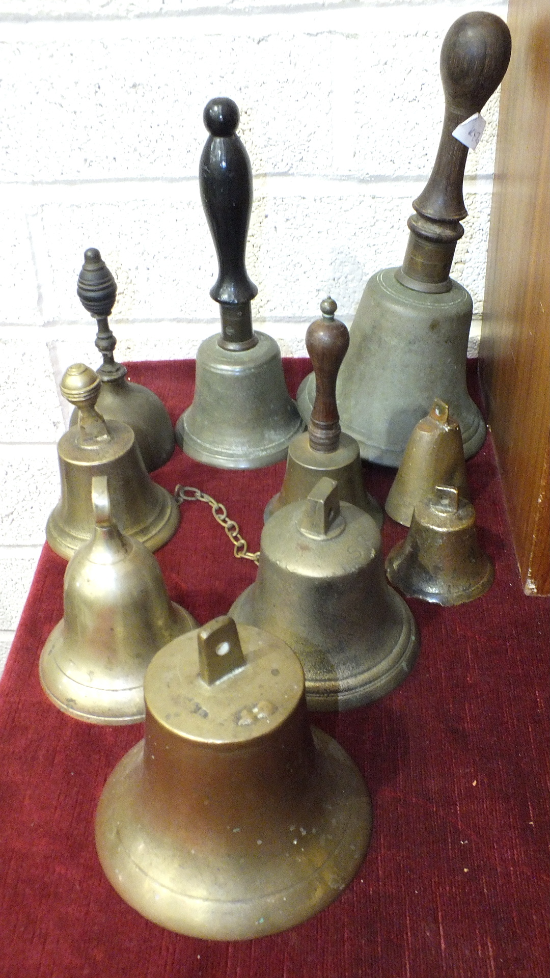 A rosewood-handled hand bell with iron clapper, 30cm high and nine other hand bells, (10).