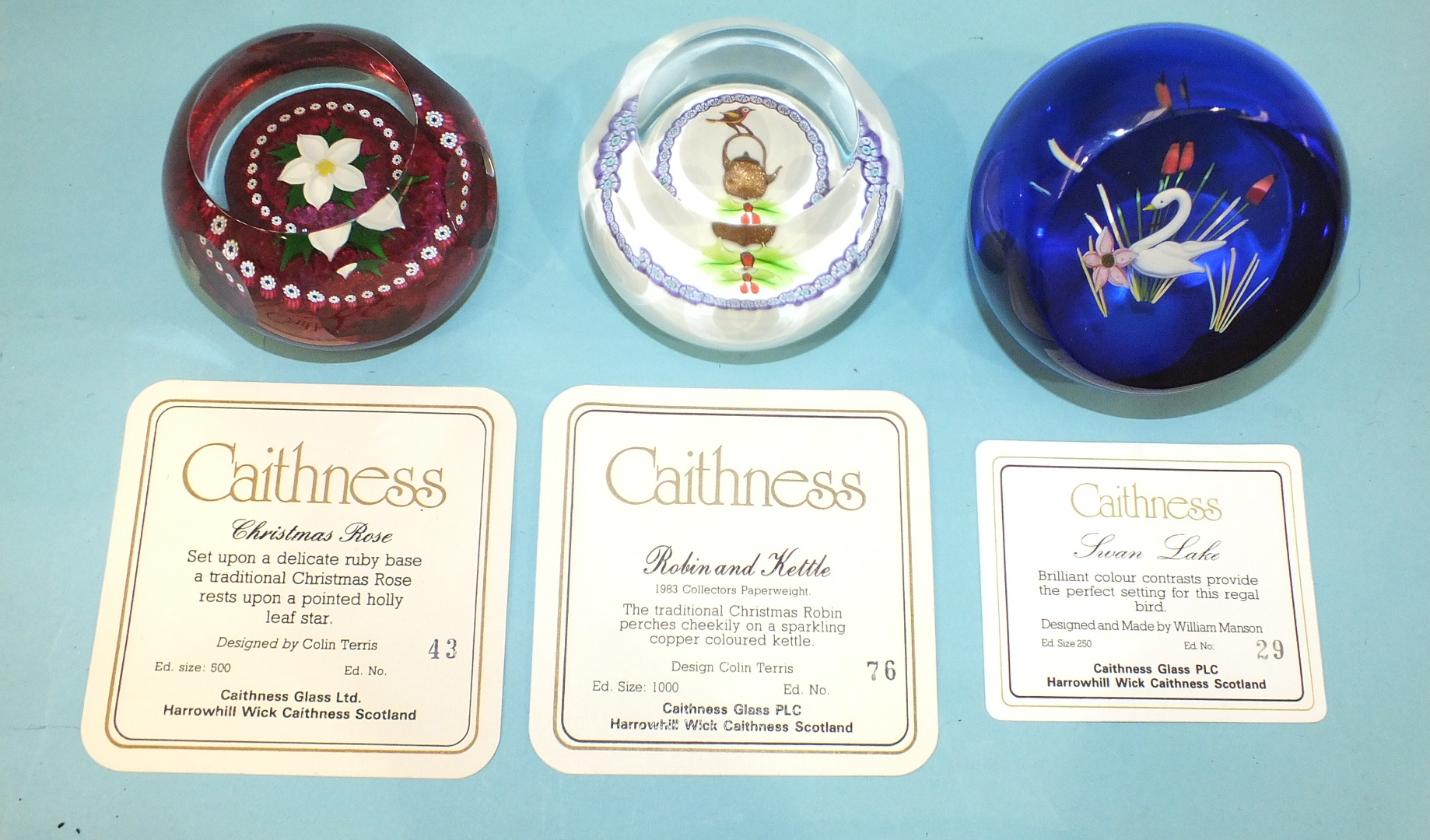 Three limited-edition Caithness glass paperweights, 'Robin and kettle' 76/1000, 'Christmas Rose'