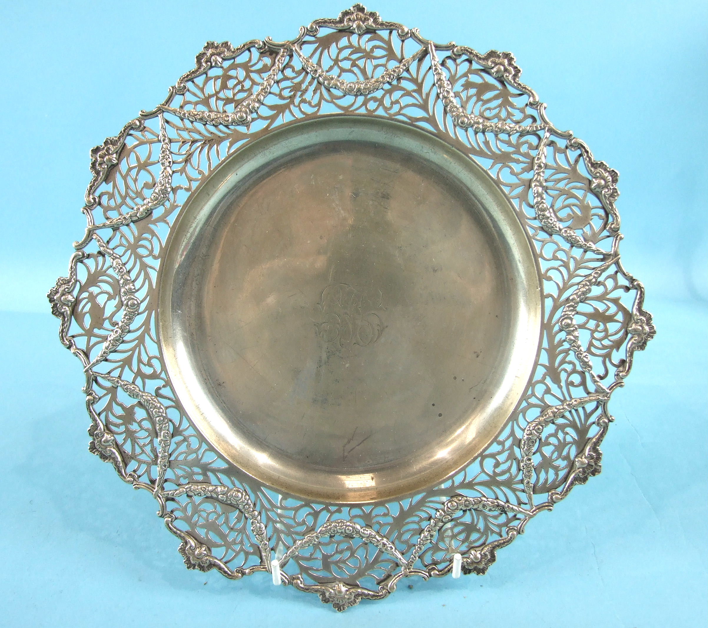 A circular shallow dish, the pierced border with foliate edge and hung with garlands of flowers,