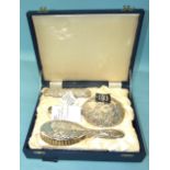 A reproduction silver dressing table set embossed with winged cherubs, in fitted case.