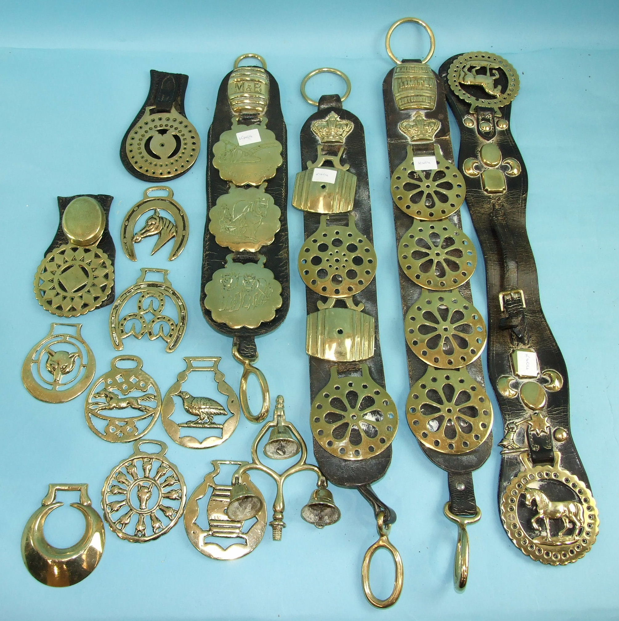 A collection of vintage and modern horse brasses, some mounted on leather straps.