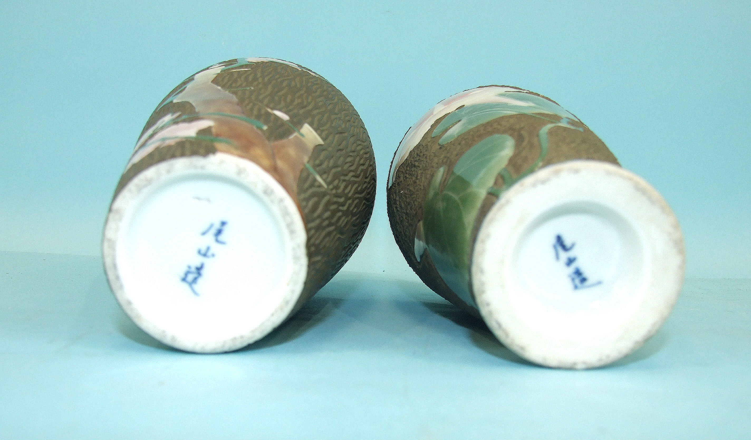 A pair of Japanese porcelain vases decorated with flowering lilies and prunus, on a wood-effect - Image 2 of 2